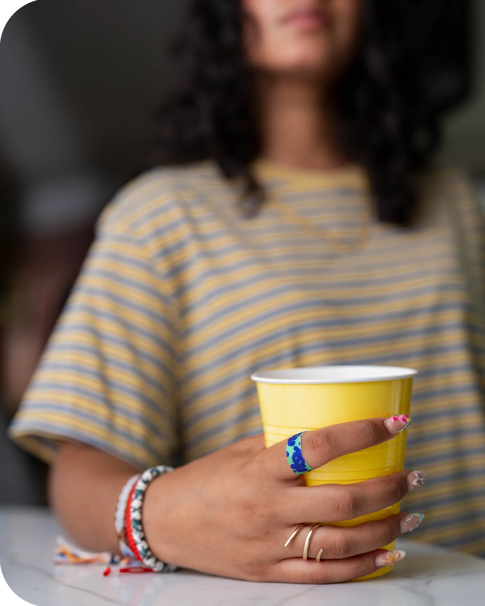 Young woman holding a yellow cup with an itsy fabric bandage wrapped around her finger